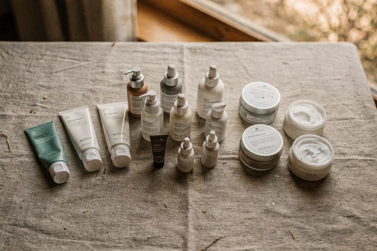 All twelve skincare containers grouped by type on a linen table