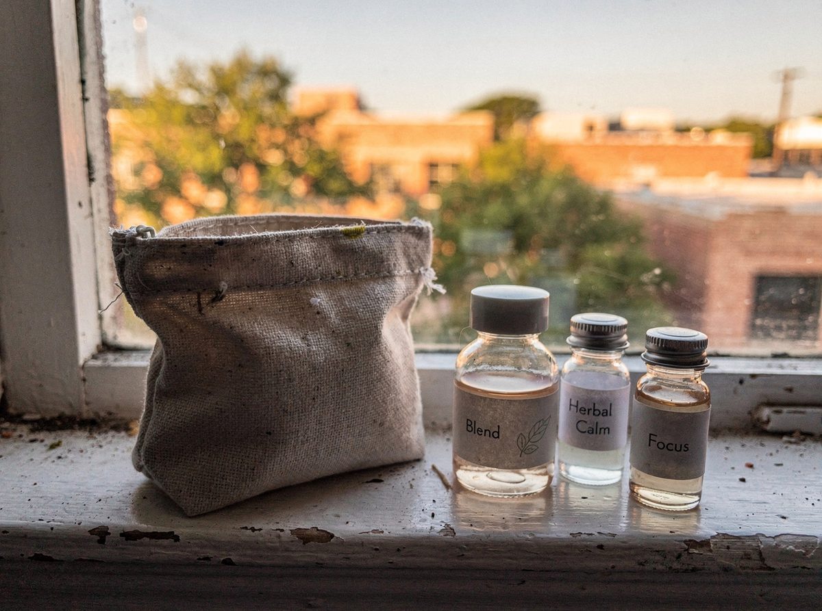 A travel pouch with four miniature skincare bottles on a windowsill