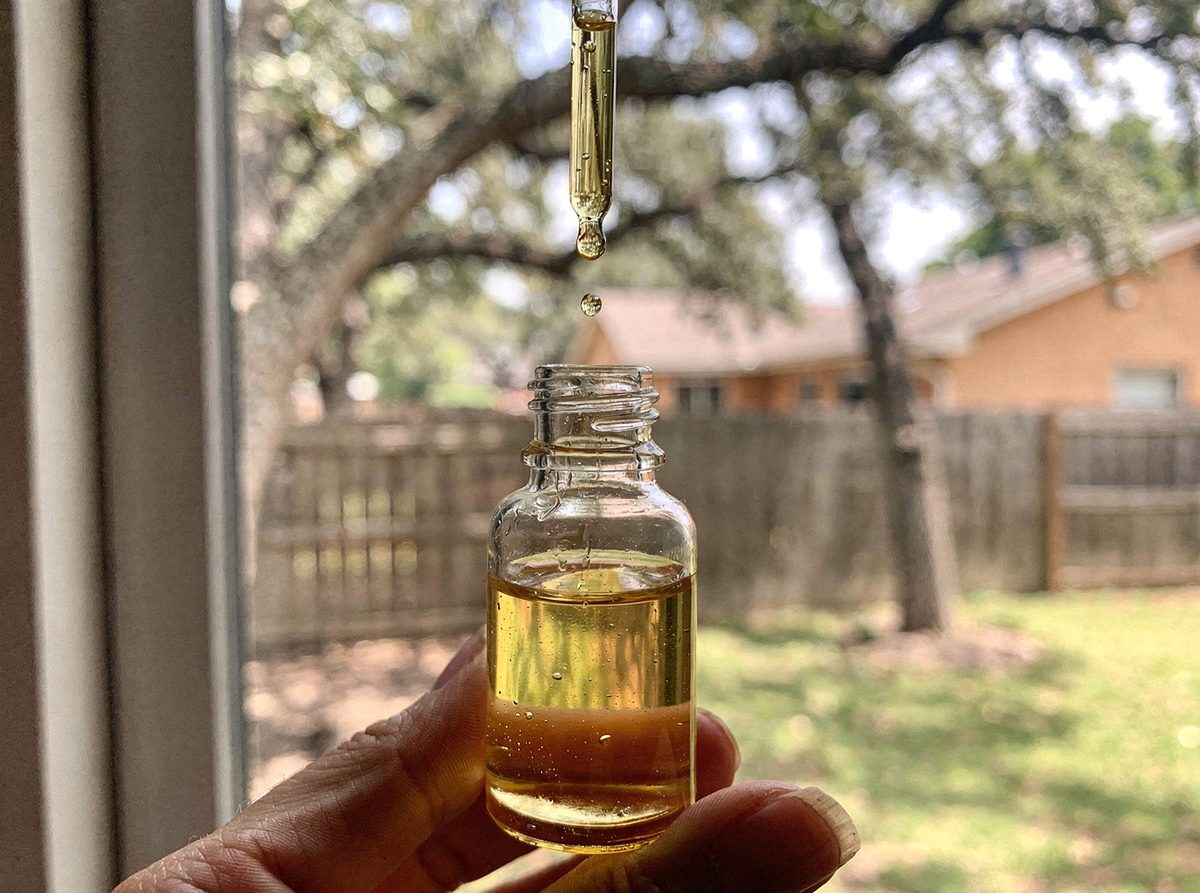 A dropper bottle of facial oil with a drop of oil falling